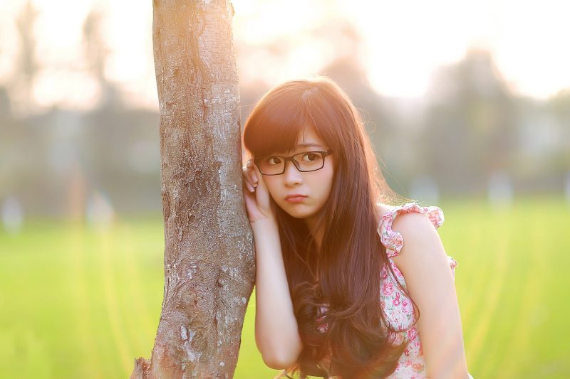 ảnh gái xinh đeo kính đứng cạnh thân cây