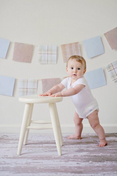 Ảnh baby dễ thương đứng bên chiếc ghế